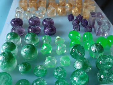 photo of resin beads various shapes in green, purple, and gold