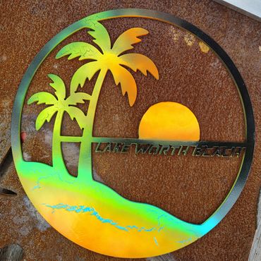 Colorful metal art depicting palm trees and sunset at Lake Worth Beach.