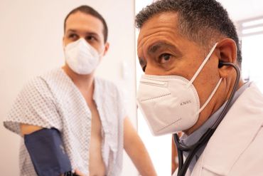 Male doctor takes the blood pressure of a patient.