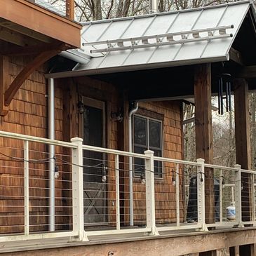 Wooden house porch with a ladder on the metal roof.
