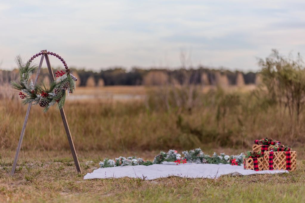 Rustic Christmas wreath and gift setup in an outdoor field.