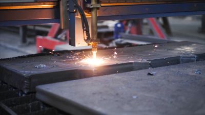CNC plasma cutting machine cutting metal with sparks flying.