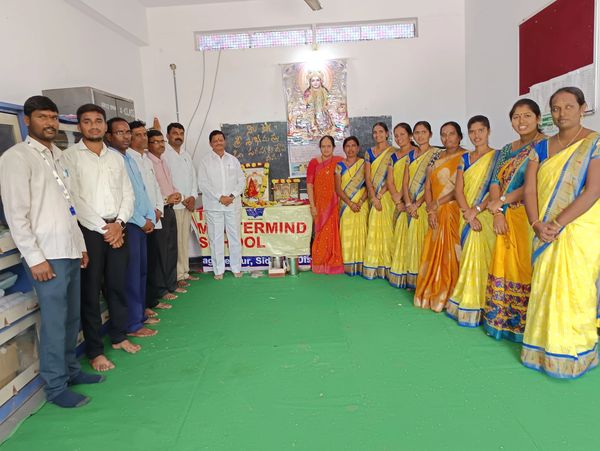 Group photo of men and women in traditional attire inside a room.