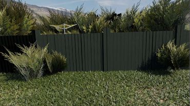 A green lawn with a green fence and laundry hanging line against a mountainscape.