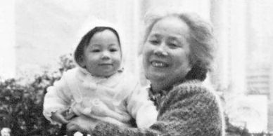 A young child is held by an older woman of Asian descent