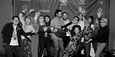 A group of people smiling and laughing in front of a step and repeat that says "SDAFF"