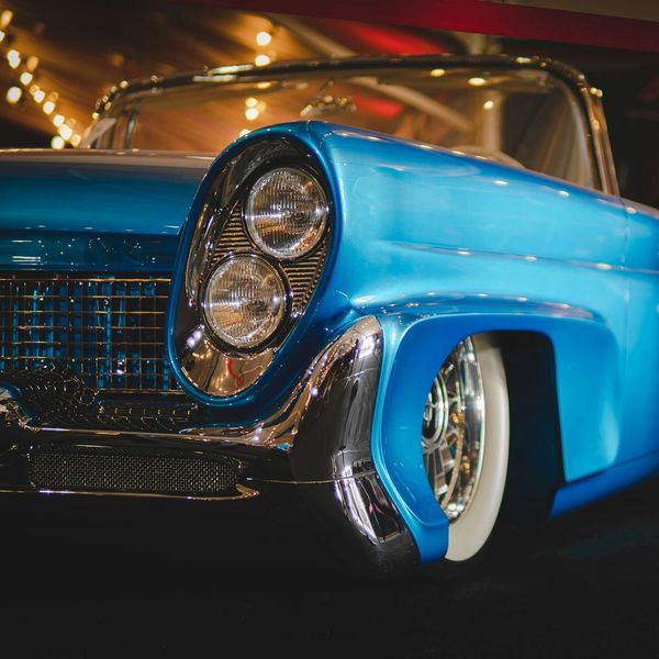 Classic blue car on showroom floor.