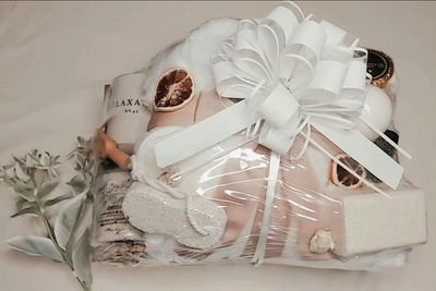 Photo taken by customer of a spa gift baskets and eucalyptus plant sitting on a white comforter.