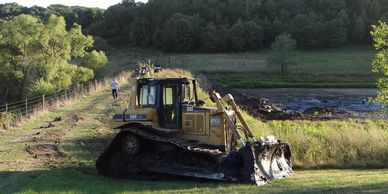 A bulldozer parked on grassy land near a path with people walking.