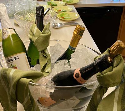 Bottles of champagne chilling in an ice-filled bucket with green napkins.