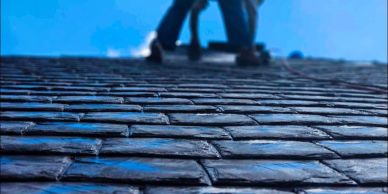 Person climbing a brick wall under a clear blue sky.