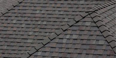 Close-up of a dark shingled roof with multiple ridges and valleys.