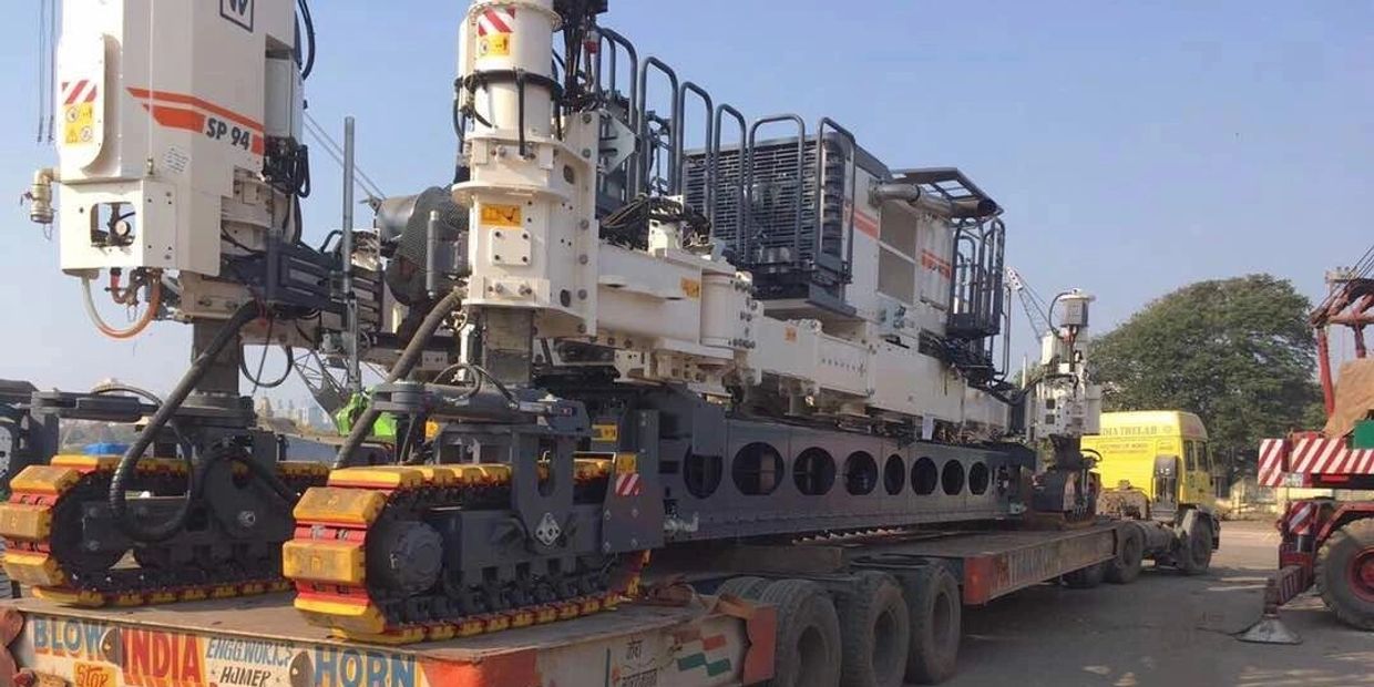 Large industrial drilling machine loaded on a flatbed truck for transport.