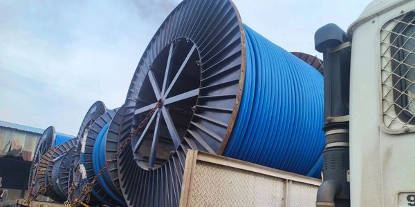 Large industrial spools with blue cables loaded on a truck.