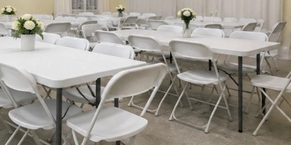 Rows of white folding chairs and tables with floral centerpieces.