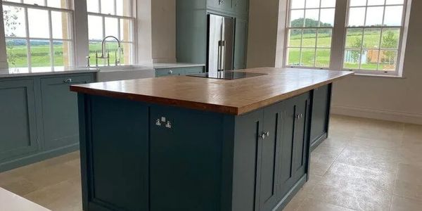 Large blue-green sprayed kitchen island with wooden worktop