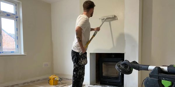 Painter from RH Smith using a paint roller to paint a wall cream