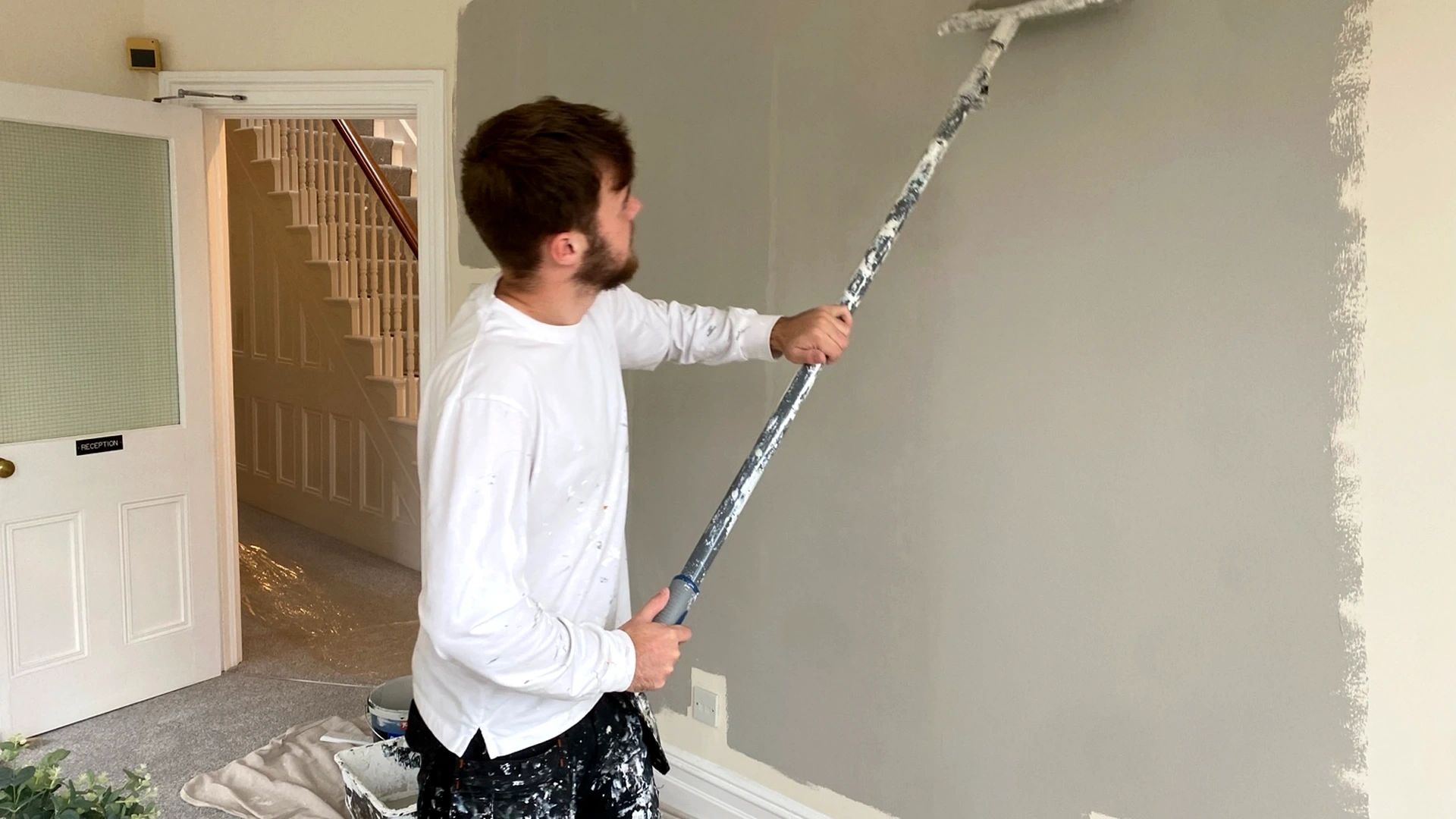 Professional painter rolling grey paint onto a living room wall in a Malvern home.