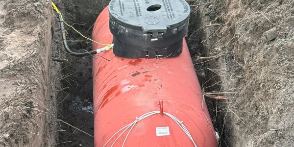 A large red underground storage tank being installed.