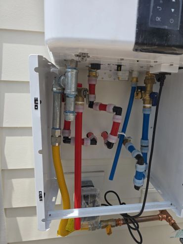 Exposed plumbing with red and blue piping inside a white box.