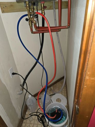Water pipes with blue and red hoses connected in a small utility space.