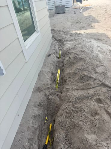 Trench with caution tape beside a house.