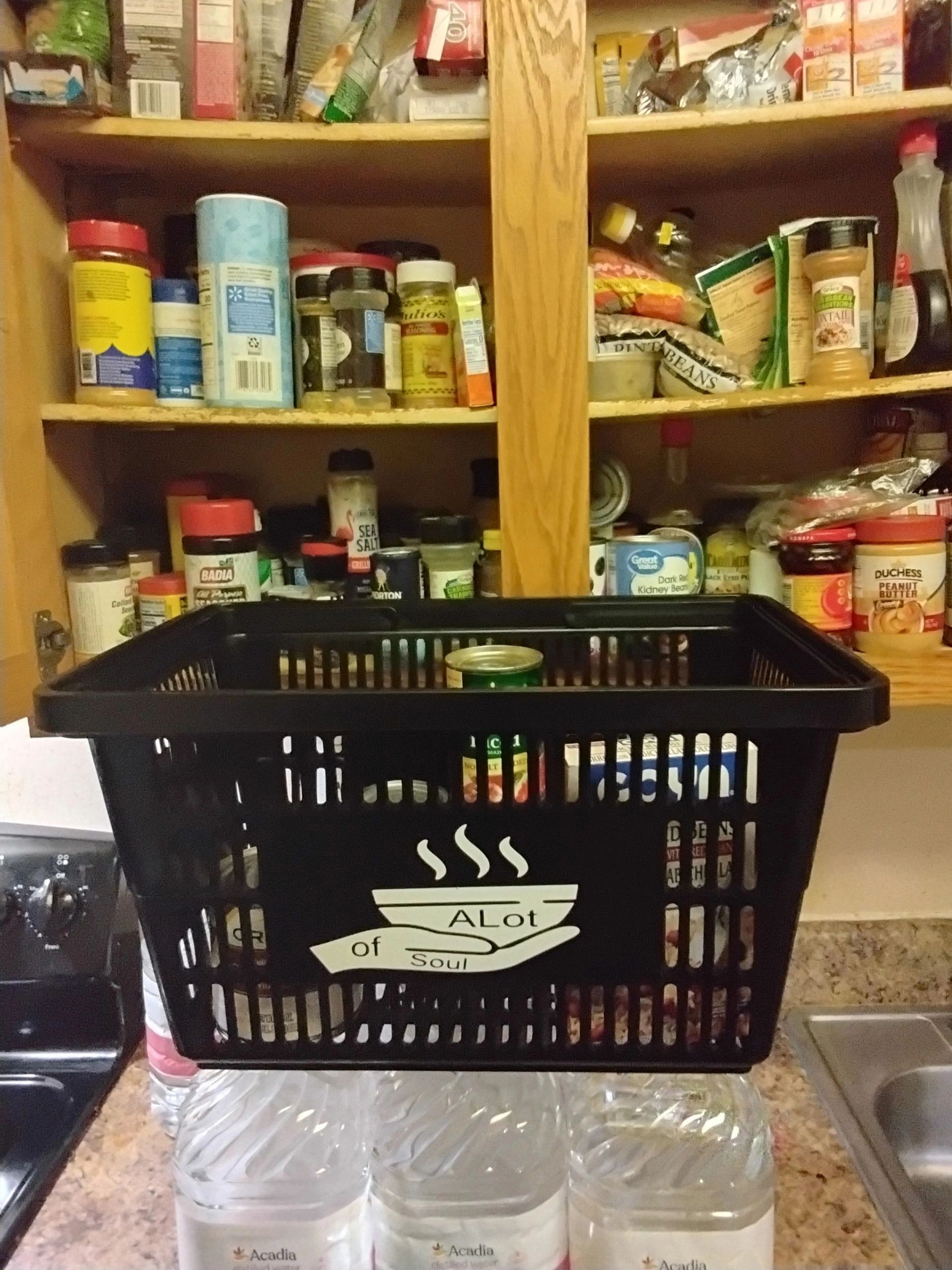 Black basket labeled 'A Lot of Soul' in front of a stocked kitchen pantry.