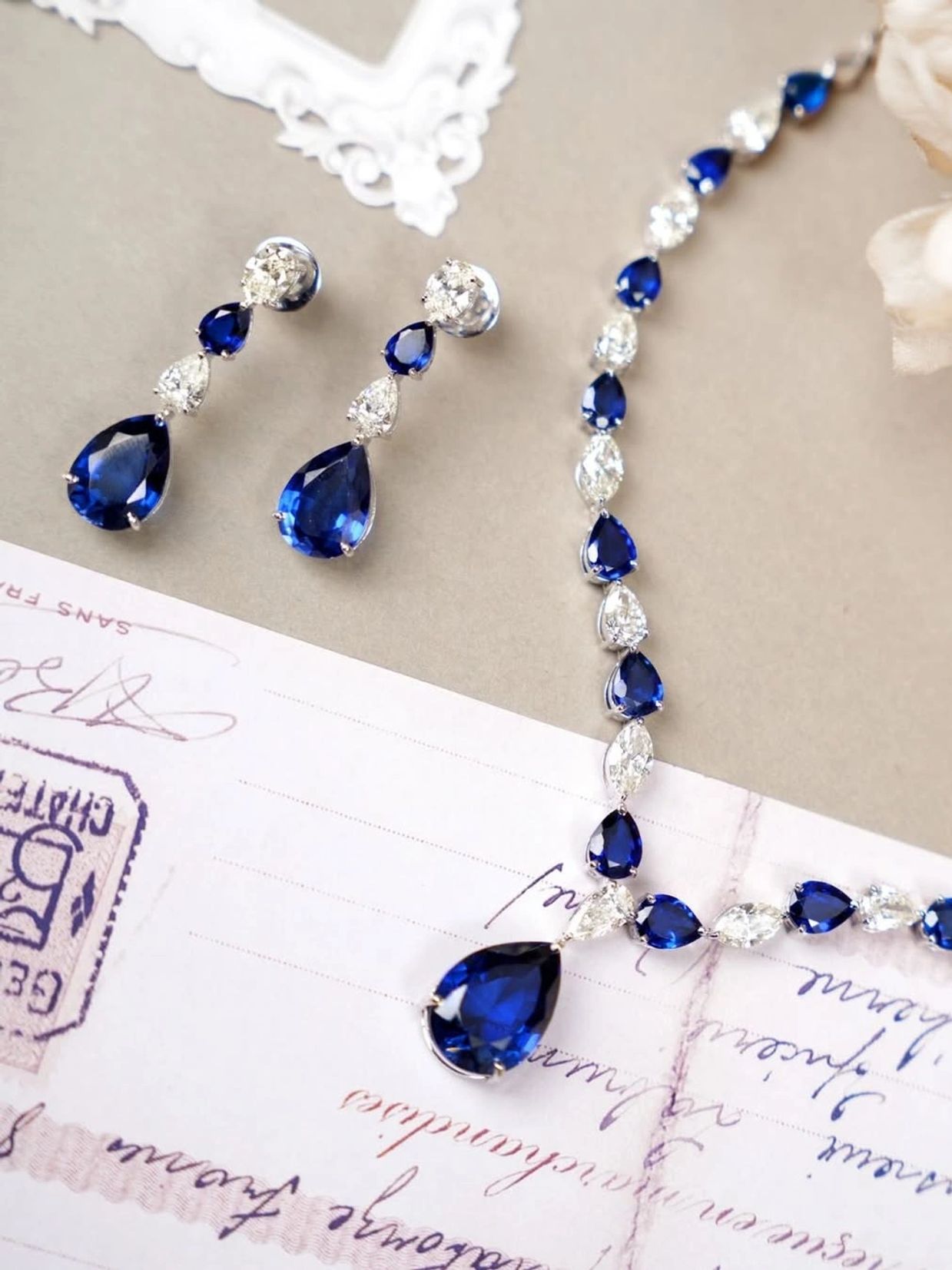 Elegant sapphire and diamond necklace with matching earrings on vintage paper.