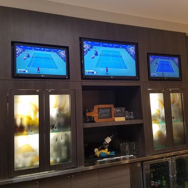 Three TVs showing a tennis match above a bar area.