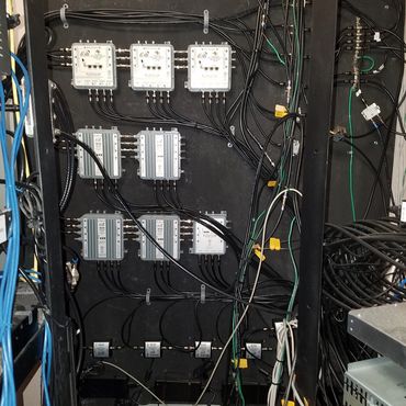 A panel of Dish Network signal amplifiers and splitters with numerous cables connected.