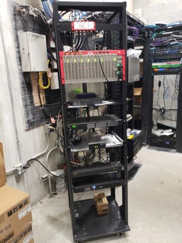 A server rack with network equipment and cables in a utility room.