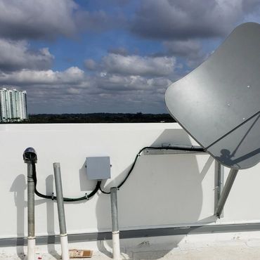 Satellite dish installed on a rooftop against a cloudy sky.