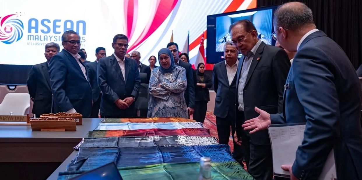 ASEAN officials examine colorful fabric samples at a conference table.
