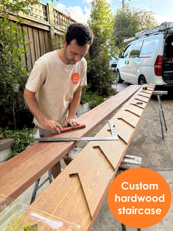 Man working on custom hardwood staircase outdoors.