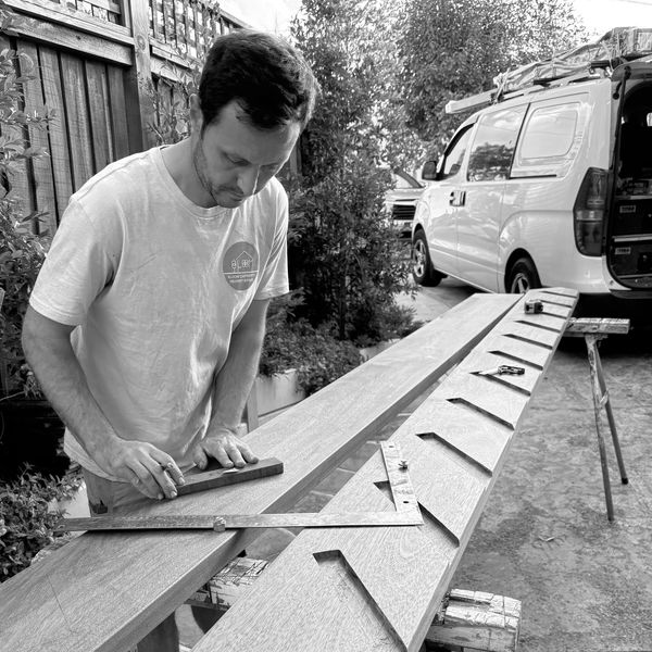 Man sanding wooden boards outdoors.