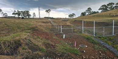 Rural fence design with steel frame and structure through flood way to prevent wash away.
