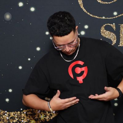 Man wearing glasses and black t-shirt with red logo, pointing at the logo.