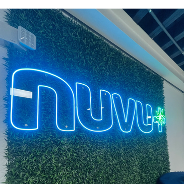 Blue neon sign reading 'Nuvu' with a green leaf on a green wall.