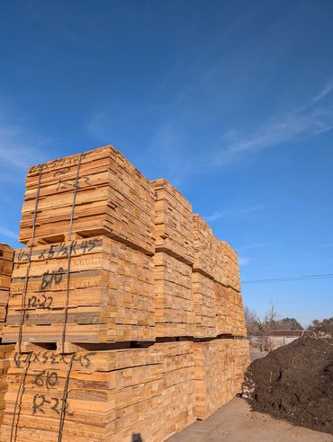 Stacks of lumber neatly piled under a clear blue sky.