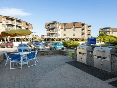 Outdoor barbeque area with seating near apartment buildings.
