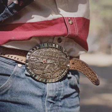 Close-up of ornate cowboy belt buckle with leather belt and jeans.