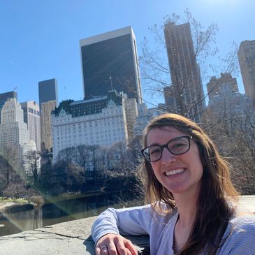 Woman smiling in front of city skyline on a sunny day.