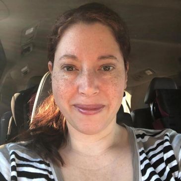 Woman with freckles smiling in a car.