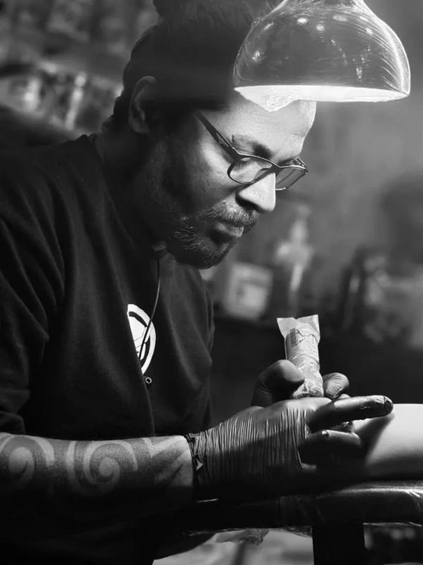 Man concentrating while tattooing with gloves and glasses.