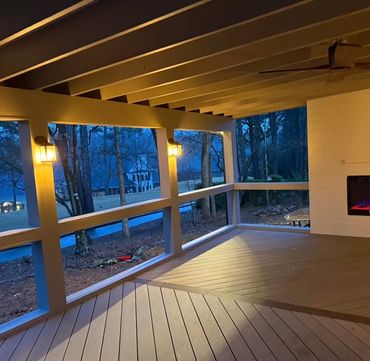 Cozy covered porch with warm lighting and a modern fireplace at dusk.