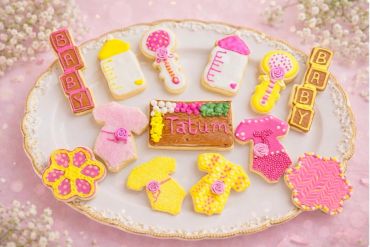 Decorated baby-themed cookies with pastel colors on a fancy plate.
