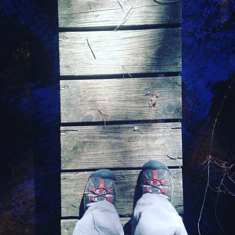 a pair of feet on a small bridge over a creek