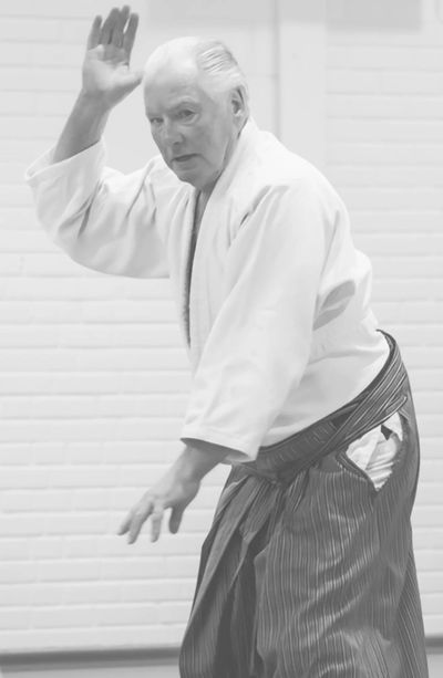 Elderly man practicing martial arts with focused expression.