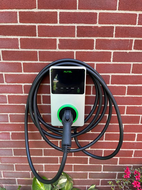 Electric vehicle charger mounted on a brick wall with coiled cable.