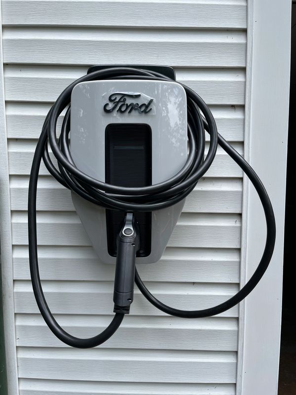 Ford electric vehicle charging station mounted on a white wall.